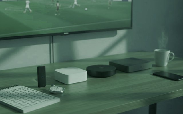 Five streaming devices, a notebook scoring grid and a stopwatch in front of a TV showing a football match