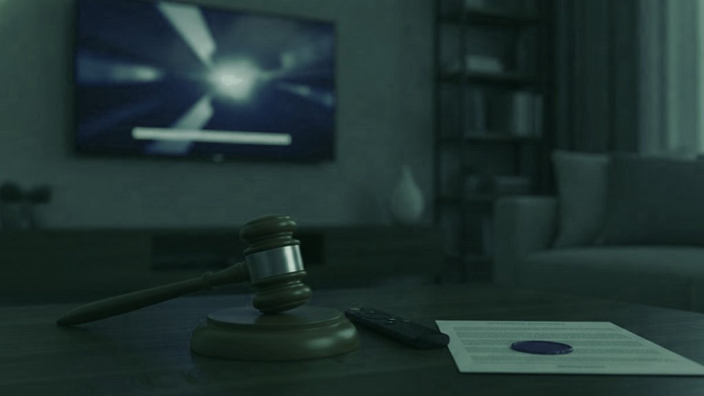 A judge gavel, a streaming remote and a sealed document on a coffee table in front of a TV