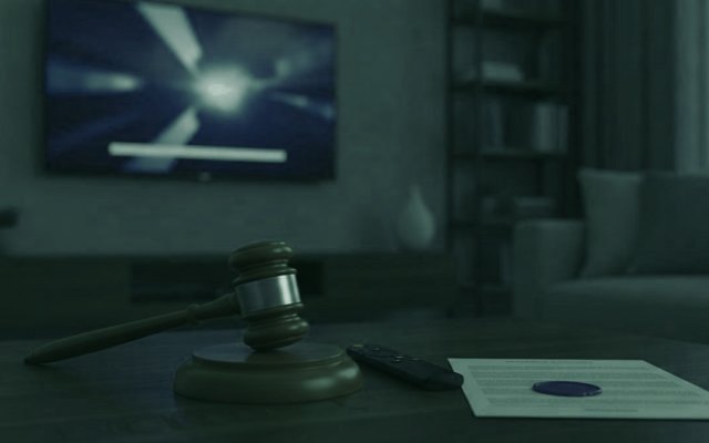 A judge gavel, a streaming remote and a sealed document on a coffee table in front of a TV